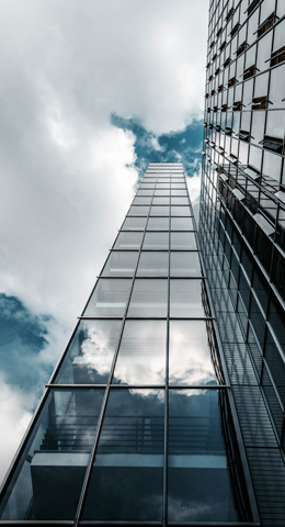 Tall glass building with an upward low angle view showing the design.