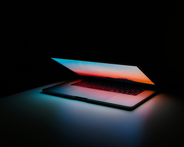  Laptop on a black background with the screen opening up showing technological capabilities.